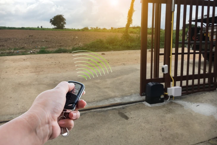Une personne assise dans un véhicule utilise une télécommande de garage pour ouvrir une porte sectionnelle blanche