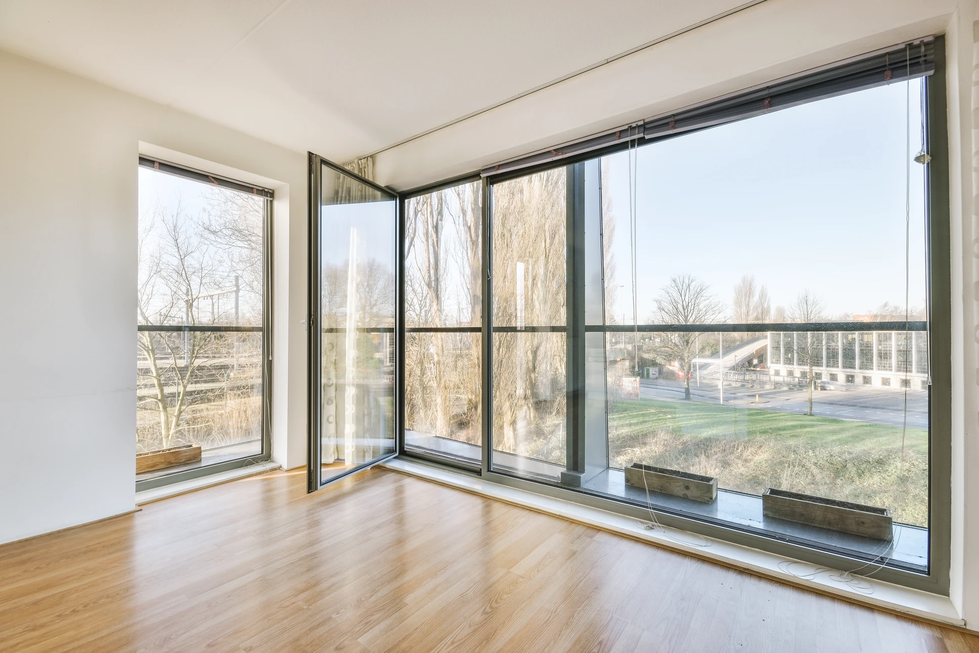Terrasse moderne d'une maison contemporaine avec deux grandes baies vitrées équipées de volets roulants électriques gris anthracite partiellement abaissés