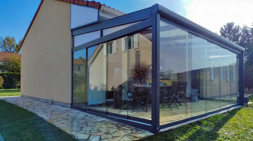 Extérieur résidentiel avec véranda vitrée moderne attenante à maison traditionnelle