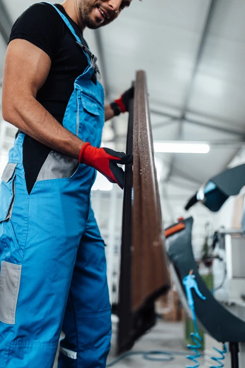 Deux ouvriers d'usine assemblant des cadres de fenêtres en PVC sur une ligne de production, démontrant le travail d'équipe et les compétences dans un environnement industriel occupé